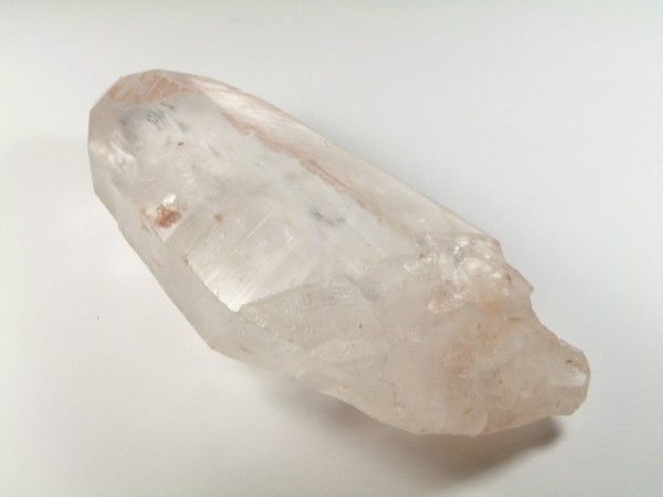 Przezroczysty kryształ kwarcu leżący na białym tle.