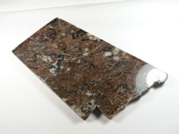 Prostokątny fragment brązowego marmuru o nieregularnej, uszkodzonej krawędzi.
