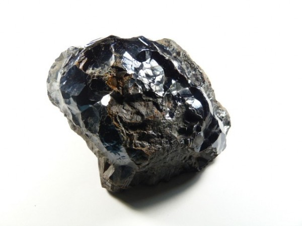 Hematyt - kamień naturalny, surowy, nieszlifowany. Czarny, błyszczący kamień hematyt na białym tle.