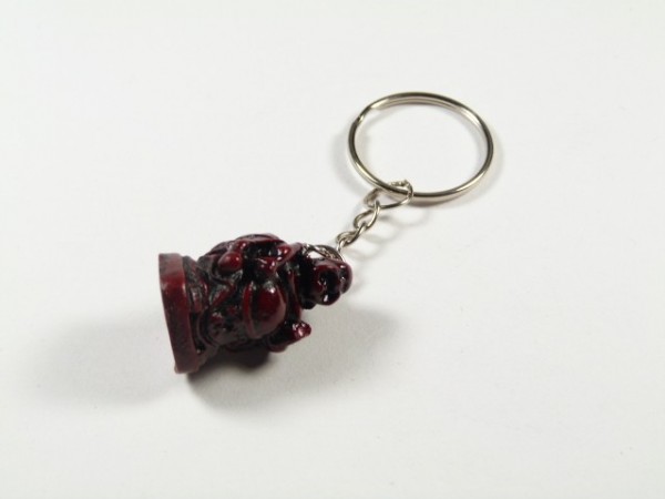 Breloczek z figurką Buddy w ciemnoczerwonym kolorze na białym tle.