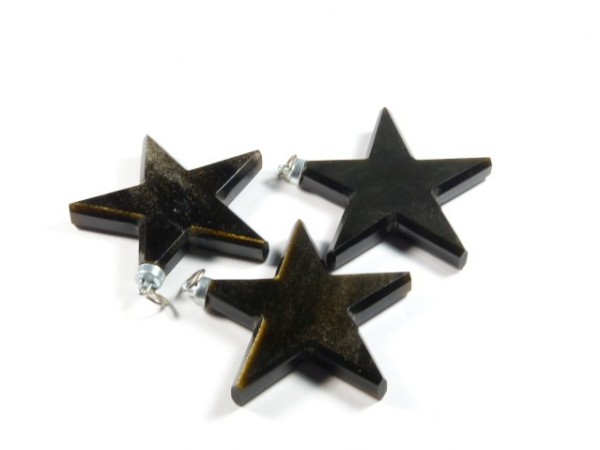 Trzy czarne, gwiaździste zawieszki leżą na białym tle.