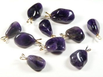 Dziesięć fioletowych wisiorków z ametystu na białym tle, każdy z metalową zawieszką.