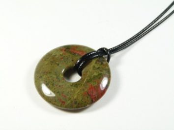 Okrągły wisiorek z zielonego kamienia z czerwonymi plamkami na czarnym sznurku.
