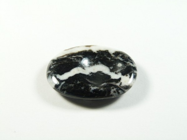 Jaspis zebra - płaski, szlifowany kamień. Czarny, wypolerowany kamień z białymi żyłkami na białym tle.