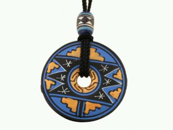 Okrągły wisiorek z niebiesko-żółtym wzorem etnicznym zawieszony na czarnym sznurku.