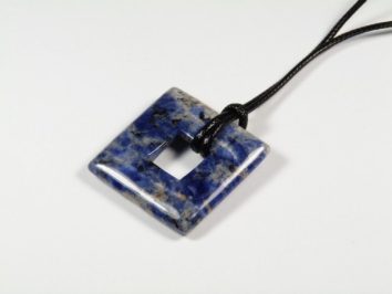 Niebieski kwadratowy wisiorek z kamienia na czarnym sznurku, widok z góry.
