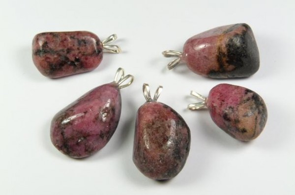 Pięć różowo-czarnych kamieni z zawieszkami, ułożonych na białym tle.