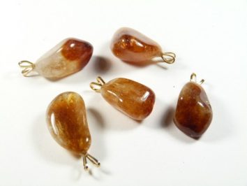 Pięć polerowanych kamieni z zawieszkami na białym tle.
