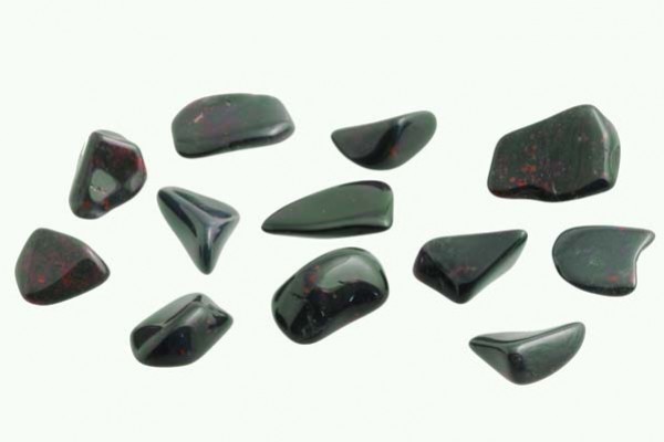 Kilka wypolerowanych, czarnych kamieni z czerwonymi plamkami na jasnym tle.