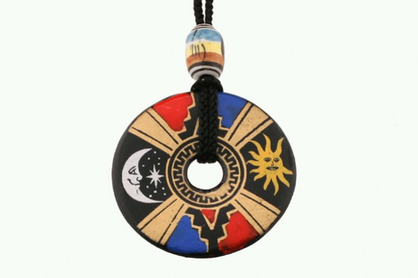 Wisiorek okrągły z symbolem słońca, księżyca i kolorowymi wzorami na czarnym tle.