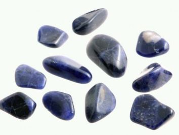 Jedenaście wypolerowanych, granatowych kamieni leży na jasnym tle.
