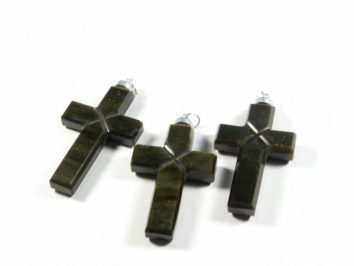 Trzy ciemne krzyżyki z kamienia, ułożone obok siebie na białym tle.