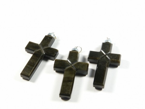 Trzy ciemne krzyżyki z kamienia, ułożone obok siebie na białym tle.