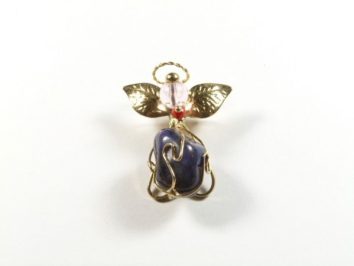 Złota zawieszka w kształcie aniołka z fioletowym kamieniem i złotymi skrzydłami na białym tle.