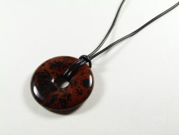 Brązowo-czarny kamienny wisior na czarnym sznurku, leżący na białym tle.