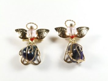 Dwa kolczyki w kształcie aniołków z kolorowymi koralikami i złotymi elementami na białym tle.