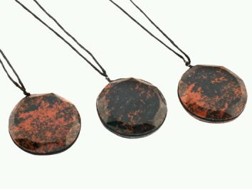 Trzy okrągłe wisiorki z czarno-czerwonego kamienia na czarnych sznurkach.