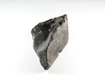 Czarny kawałek obsydianu na białym tle.