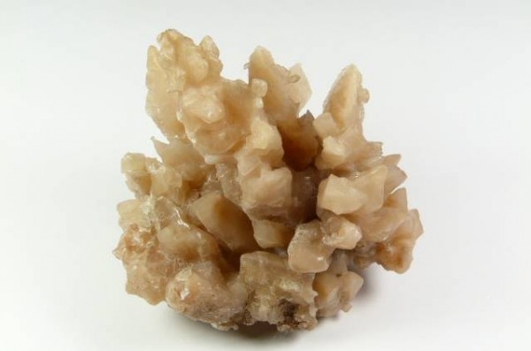 Jasnobrązowy, zbity kryształ minerału aragonitu na białym tle.