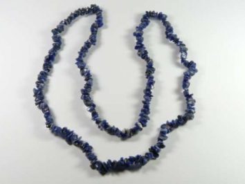 Naszyjnik z niebieskich kamieni o nieregularnych kształtach, ułożony na białym tle.