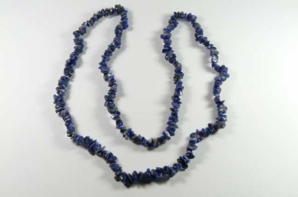 Naszyjnik z niebieskich kamieni o nieregularnych kształtach, ułożony na białym tle.