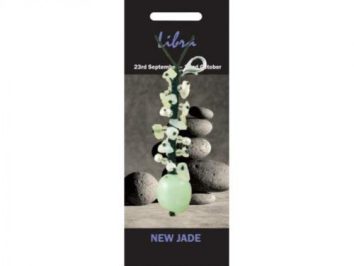 Wisiorek z jadeitu na tle ułożonych kamieni, podpis: "Libra, New Jade".