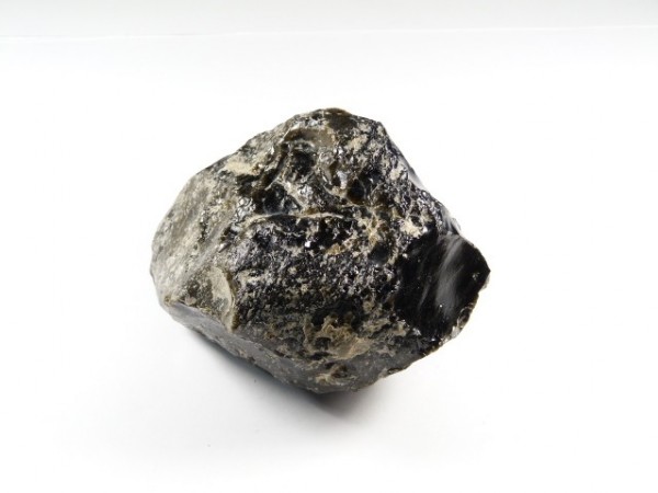 Czarny, połyskujący kamień obsydian na białym tle.
