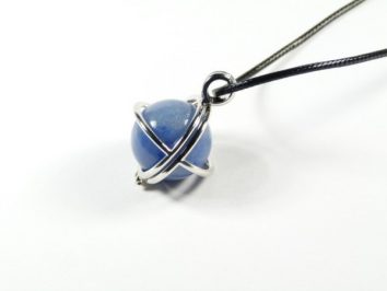 Naszyjnik z niebieską kulką otoczoną metalowym pierścieniem na czarnym sznurku.