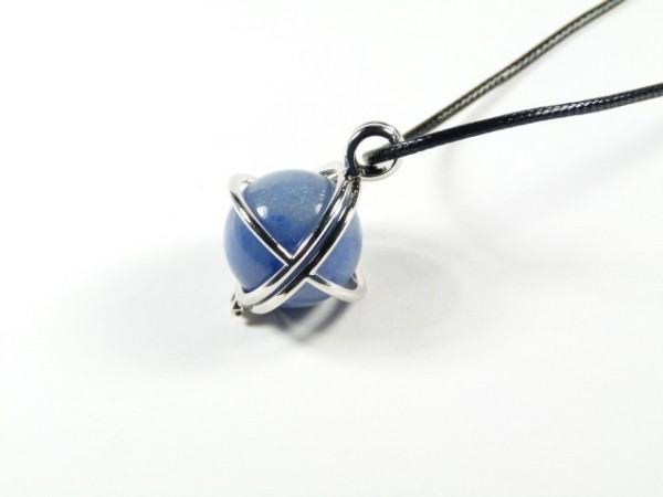 Naszyjnik z niebieską kulką otoczoną metalowym pierścieniem na czarnym sznurku.