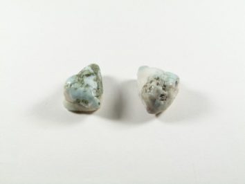 Dwa nieoszlifowane kamienie larimaru na białym tle.