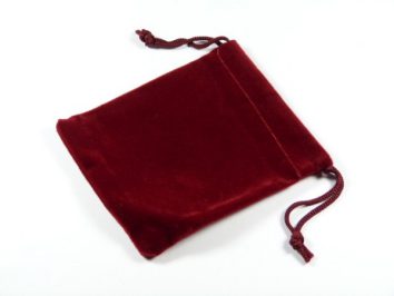 Bordowy woreczek z materiału zamykany na sznurek, leży na białym tle.