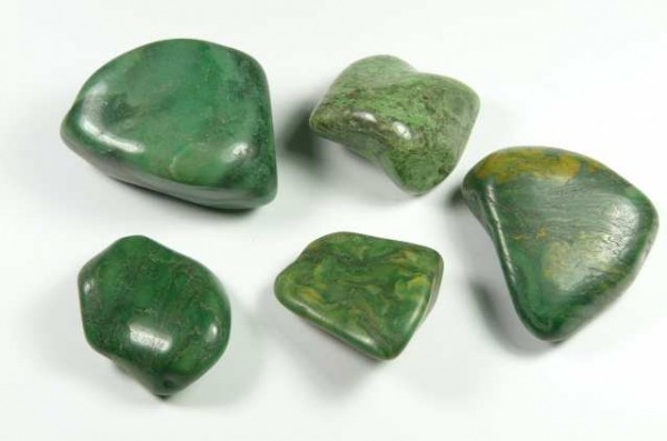 Pięć zielonych, wygładzonych kamieni leży na białym tle.