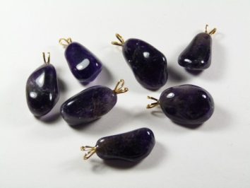 Siedem fioletowych zawieszek z ametystu na białym tle.