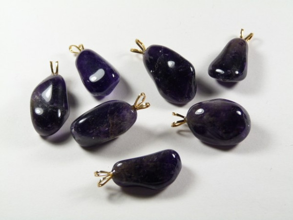 Siedem fioletowych zawieszek z ametystu na białym tle.