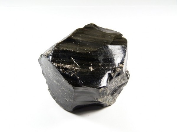Czarny, błyszczący kawałek obsydianu na białym tle.