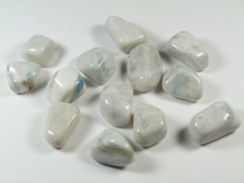 Kilka gładkich, białych kamieni leży na jasnym tle.