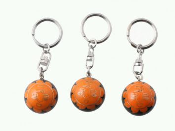 Trzy breloczki z pomarańczowymi piłkami do kluczy ustawione obok siebie na białym tle.