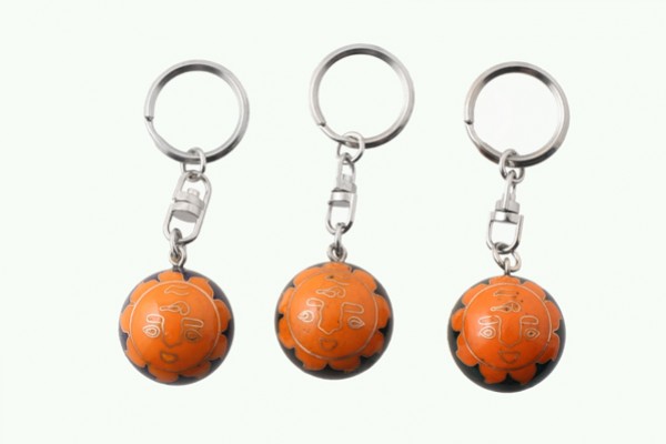 Trzy breloczki z pomarańczowymi piłkami do kluczy ustawione obok siebie na białym tle.