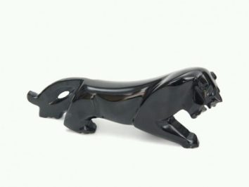 Czarna, błyszcząca figurka pantery w pozycji do ataku na białym tle.