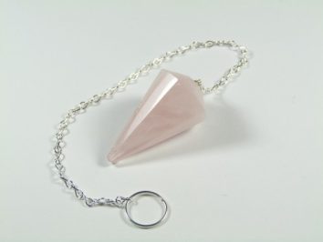 Różowy wahadełko z kamienia na srebrnym łańcuszku leży na białym tle.