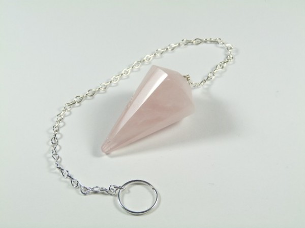Różowy wahadełko z kamienia na srebrnym łańcuszku leży na białym tle.