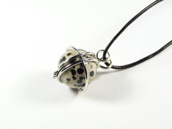Wisiorek z czarnego sznurka z kamieniem w kropki, oplecionym drutem metalowym.