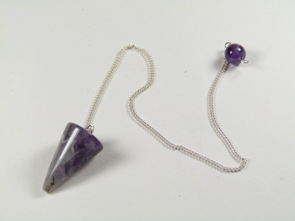 Wahadełko ametyst stożek. Wahadełko z fioletowego kamienia na srebrnym łańcuszku, leżące na białym tle.