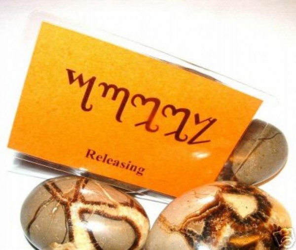 Pomarańczowa karta z napisem "Releasing" obok trzech brązowych kamieni.