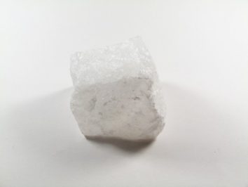 Biały, półprzezroczysty kryształ soli na białym tle.