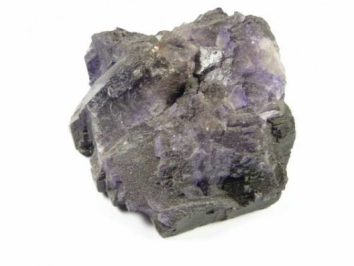 Fluoryt - kamień naturalny, surowy, nieszlifowany. Fioletowy kryształ na białym tle.
