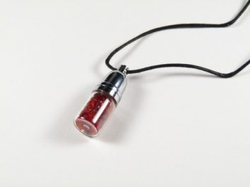 Buteleczka andara czerwona wisiorek. Wisiorek na czarnym sznurku z małym szklanym słoiczkiem wypełnionym czerwonymi drobinkami.