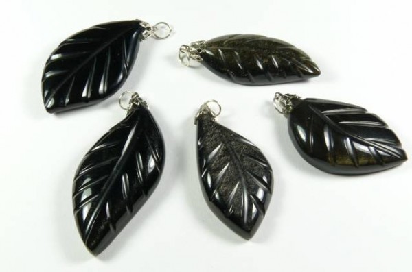 Pięć czarnych wisiorków w kształcie liści leży na białym tle.