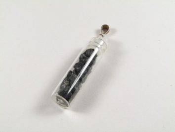 Buteleczka wisiorek czarny turmalin. Przezroczysta fiolka z czarnymi kamykami, zawieszona na metalowym uchwycie.