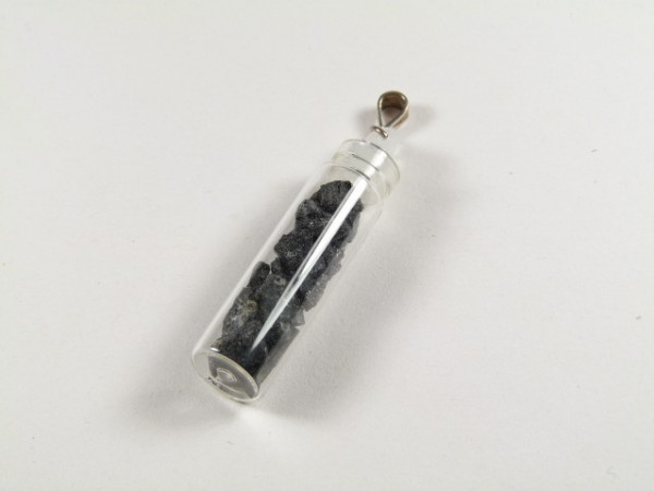 Buteleczka wisiorek czarny turmalin. Przezroczysta fiolka z czarnymi kamykami, zawieszona na metalowym uchwycie.